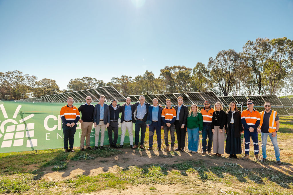 Group of people posed in front of solar panels
