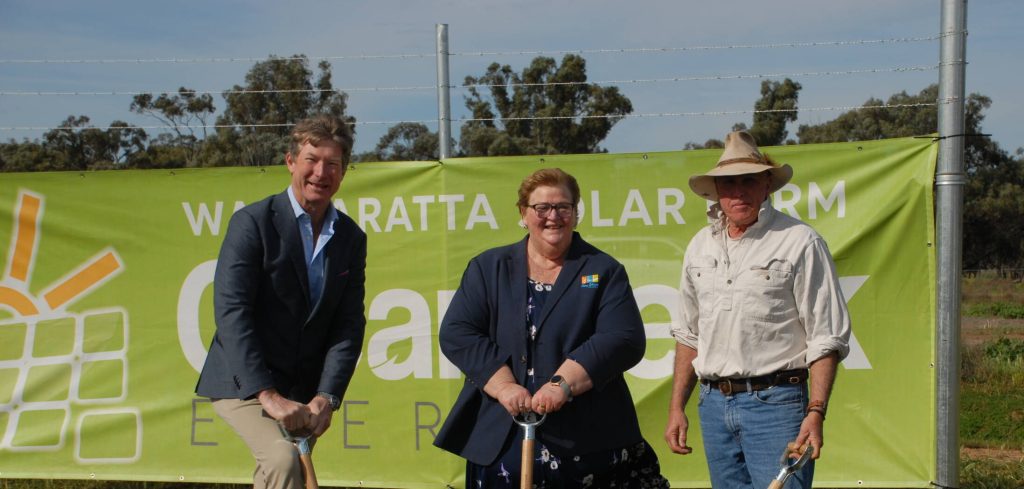 Three people holding shovels at a solar farm site