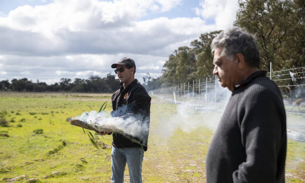 Two men holding smoking eucalyptus leaves